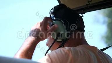 直升机飞行员戴上耳机与调度员谈判。 请求起飞许可